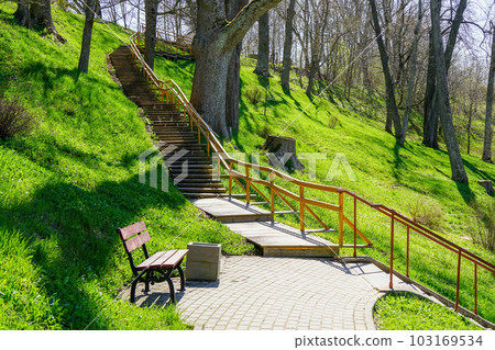 A beautiful walking path with wooden stairs in a nature park in a hilly area, springtime sunlight A beautiful walking path with wooden stairs in a nature park in a hilly area, springtime sunlight 103169534