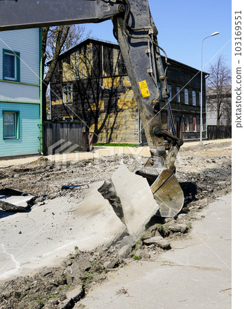 Crawler excavator bucket dismantle the old asphalt layer before the reconstruction of the street 103169551