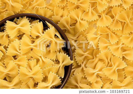 Raw farfalle pasta in a bowl close-up, top view. Italian food Raw farfalle pasta in a bowl close-up, top view. Italian food 103169721