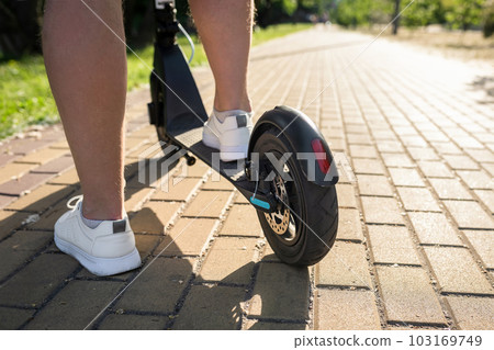 Man on a modern electric scooter in the park, close-up. Eco friendly transport 103169749