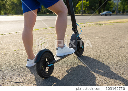 Legs of a man on an electric scooter on the road in summer. Urban transport concept 103169750