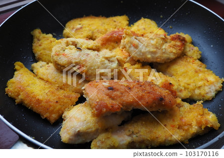 Fried chicken fillet in a black pan close-up. Many pieces of fried chicken, rolled in breadcrumbs. Homemade quick recipes for cooking and body processing of meat products. 103170116
