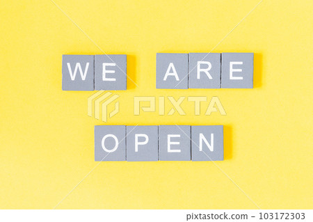 We are open quote, welcome sign for business or caffe, wooden letters on yellow background 103172303