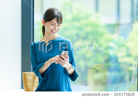 一個女人在辦公室使用智能手機 一個女人在辦公室使用智能手機 103173620