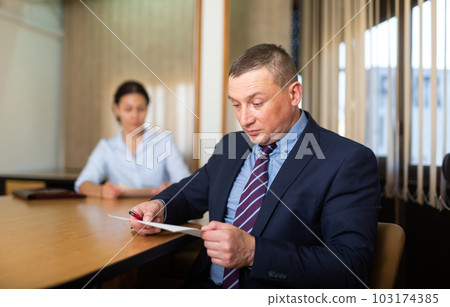 Shocked office employe reading papers with dissatisfied female manager 103174385