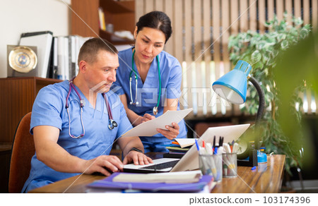 Two doctors checking patient papers in clinic Two doctors checking patient papers in clinic 103174396