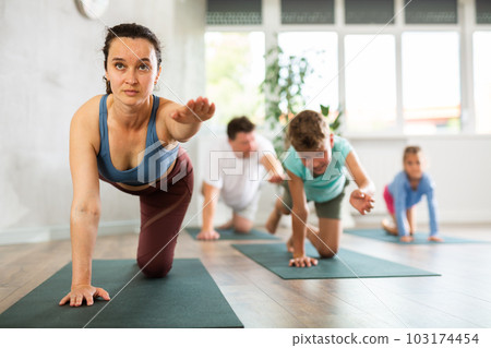 Confident mom, dad, son and daughter perform bird dog power asana Confident mom, dad, son and daughter perform bird dog power asana 103174454