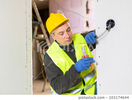 Electrician installing electricity in new house Electrician installing electricity in new house 103174644
