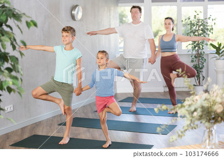 Sweet sister and brother practicing tree pose of yoga in pair 103174666