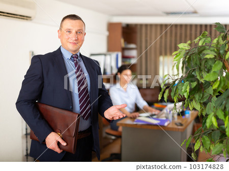 Portrait of successful businessman inviting to modern office 103174828