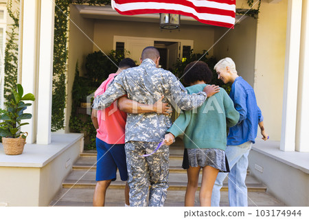 Happy diverse group of friends greeting biracial male american soldier outside the house Happy diverse group of friends greeting biracial male american soldier outside the house 103174944