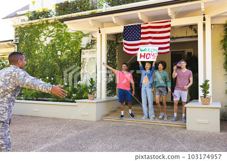 Happy diverse group of friends greeting biracial male american soldier outside the house Happy diverse group of friends greeting biracial male american soldier outside the house 103174957