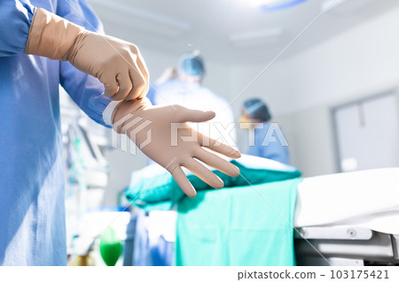 Midsection of surgeon putting on surgical gloves in operating theatre, copy space Midsection of surgeon putting on surgical gloves in operating theatre, copy space 103175421