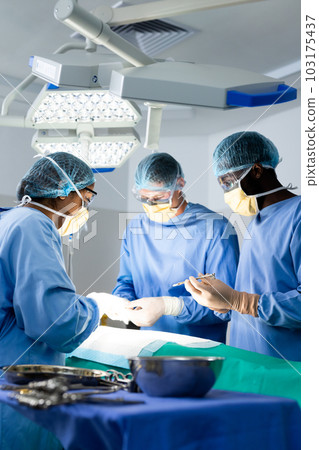 Diverse group of surgeons operating on patient in operating theatre, copy space 103175437