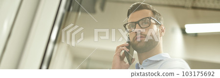 Calm man talking on the phone while entering the room Calm man talking on the phone while entering the room 103175692