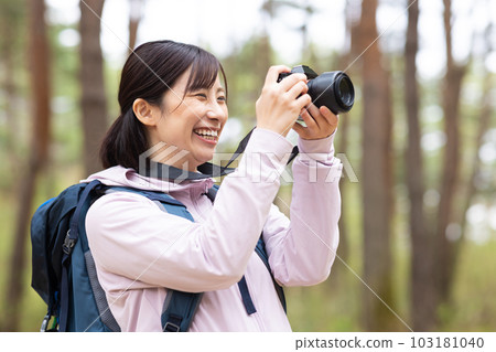 A woman hiking holding a camera 103181040