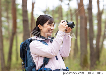 A woman hiking holding a camera 103181042