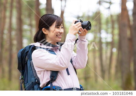 A woman hiking holding a camera 103181046