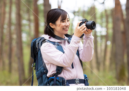 A woman hiking holding a camera 103181048
