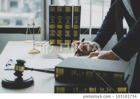 Lawyer hand holding pen and providing legal consult business dispute service at the office with justice scale and gavel hammer 103181734