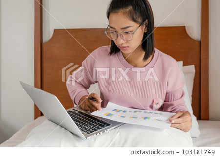 Business women bookkeeper holding pen and use laptop doing account for paying tax on on the bed, work from home concept Business women bookkeeper holding pen and use laptop doing account for paying tax on on the bed, work from home concept 103181749