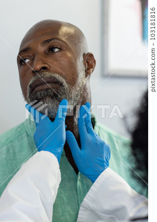 Biracial female doctor wearing medical gloves examinating african american male patient 103181816
