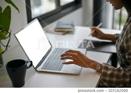 A businesswoman using her laptop computer, managing her work on laptop in her office. A businesswoman using her laptop computer, managing her work on laptop in her office. 103182080