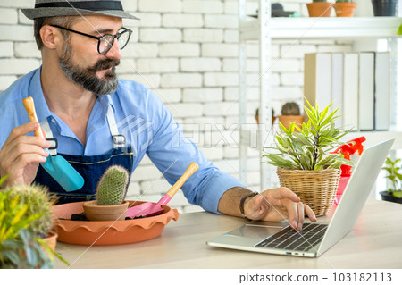 Hipster elderly men learn to take care of plants online with laptop, a hobby of urban home gardening after sustainable retirement Hipster elderly men learn to take care of plants online with laptop, a hobby of urban home gardening after sustainable retirement 103182113