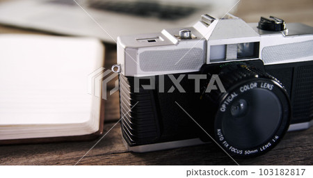 Close up of black camera and empty notebook on wooden table Close up of black camera and empty notebook on wooden table 103182817