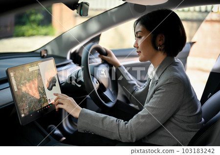A successful businesswoman using a GPS, selecting a destination on a dashboard screen A successful businesswoman using a GPS, selecting a destination on a dashboard screen 103183242