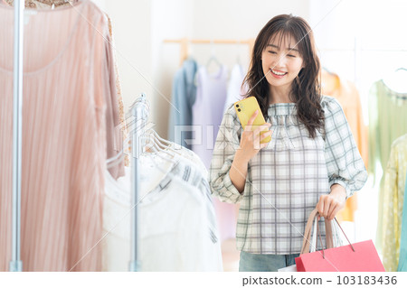 在購物中心購物時操作智能手機的年輕女性 在購物中心購物時操作智能手機的年輕女性 103183436
