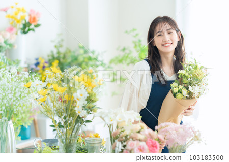 Young female clerk working in a flower shop 103183500