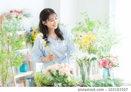Young female clerk working in a flower shop Young female clerk working in a flower shop 103183507