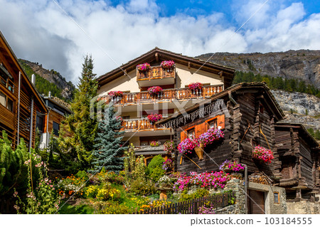 Traditional wooden alpine chalet with flowers 103184555