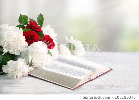 Bible and a bouquet of peonies on a table 103186373