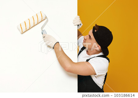 young man in working clothes painting white walls young man in working clothes painting white walls 103186614