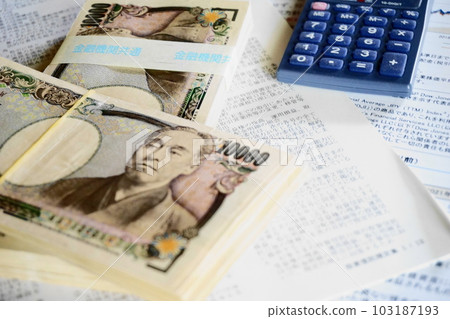 10,000 日元鈔票和一個計算器堆疊在材料上 103187193