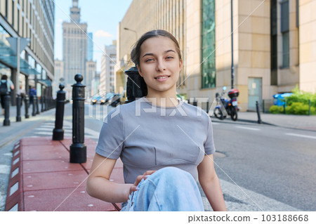 Young smiling teenage girl looking at camera on street of modern city Young smiling teenage girl looking at camera on street of modern city 103188668