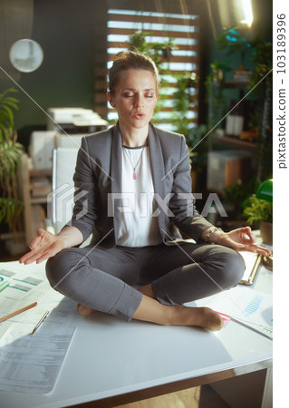 relaxed modern business woman in modern green office meditating 103189396