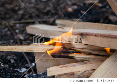 A fire burns in a campfire with a red fire in the background. A fire burns in a campfire with a red fire in the background. 103189632