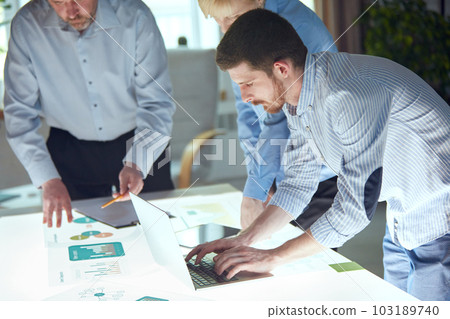 Team analyzing investment graph of money brainstorming and discussing plans in meeting room. Concept of investment, teamwork. Business people conference 103189740