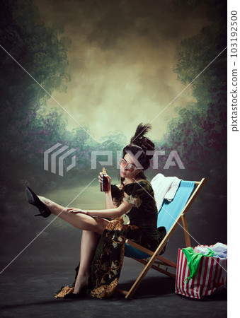 Portrait of beautiful young girl, elegant royal person in vintage dress applying sunscreen on legs against dark background. Summer vacation 103192500