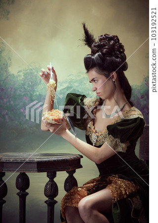 Portrait of young emotional girl, princess in retro dress eating instant noodles with dissatisfied face against dark vintage background 103192521