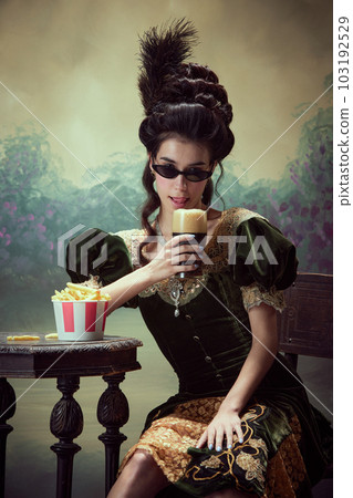 Portrait of beautfiufl young girl, princess in elegant drss and sunglasss drinking foamy beer, eating fries against dark vintage background Portrait of beautfiufl young girl, princess in elegant drss and sunglasss drinking foamy beer, eating fries against dark vintage background 103192529