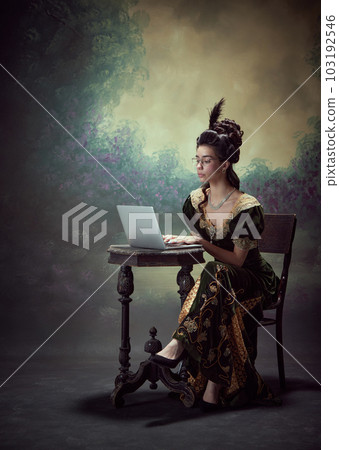 Portrait of beautiful young woman, queen in elegant dress and glasses, working with laptop against dark vintage background Portrait of beautiful young woman, queen in elegant dress and glasses, working with laptop against dark vintage background 103192546