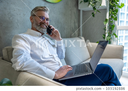 Joyful businessperson talking on the smartphone in a business center Joyful businessperson talking on the smartphone in a business center 103192886