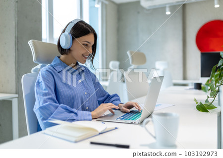 Smiling employee working on the laptop in the company office Smiling employee working on the laptop in the company office 103192973
