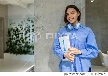 Joyous employee with papers and the portable computer standing indoors Joyous employee with papers and the portable computer standing indoors 103192974