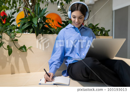 Smiling young female writing down her ideas in the notebook 103193013