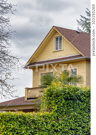 Top of yellow residential house on overcast sky background Top of yellow residential house on overcast sky background 103193269